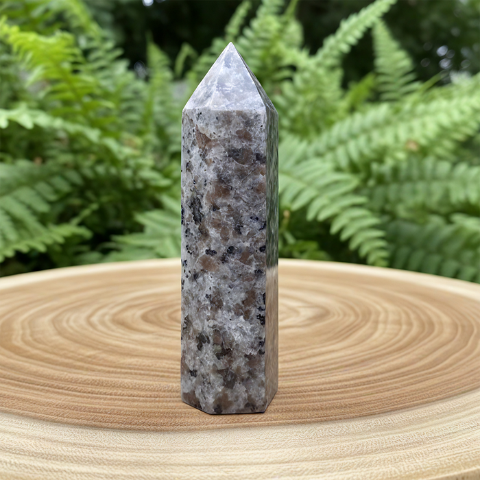 Speckled grey Yooperlite point standing on a wooden slab