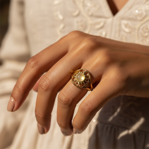 The solar glow ring worn on a hand resting against a white embroidered dress