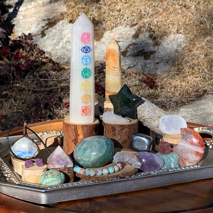 A past box laid out on a tray: a white chakra tower, crystal points, a star, tumbled stones and a bracelet