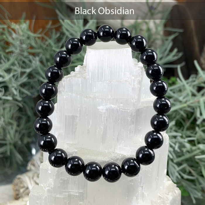 Black Obsidian bracelet with glossy deep black beads, displayed on a selenite tower