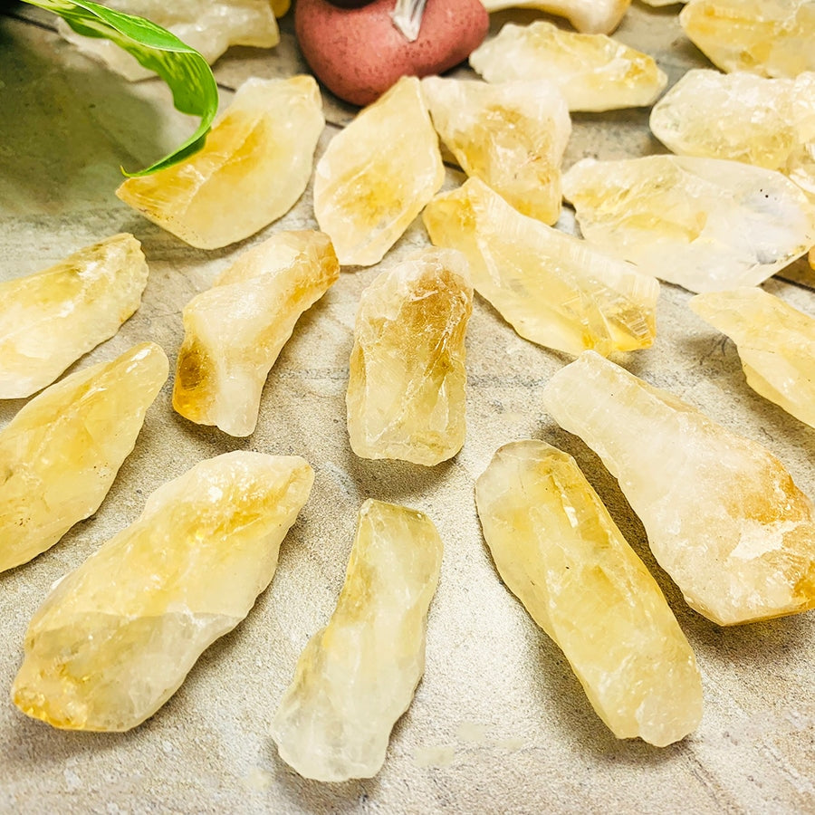 Many rough citrine shards spread on a stone surface, ranging from pale lemon to deep honey-gold