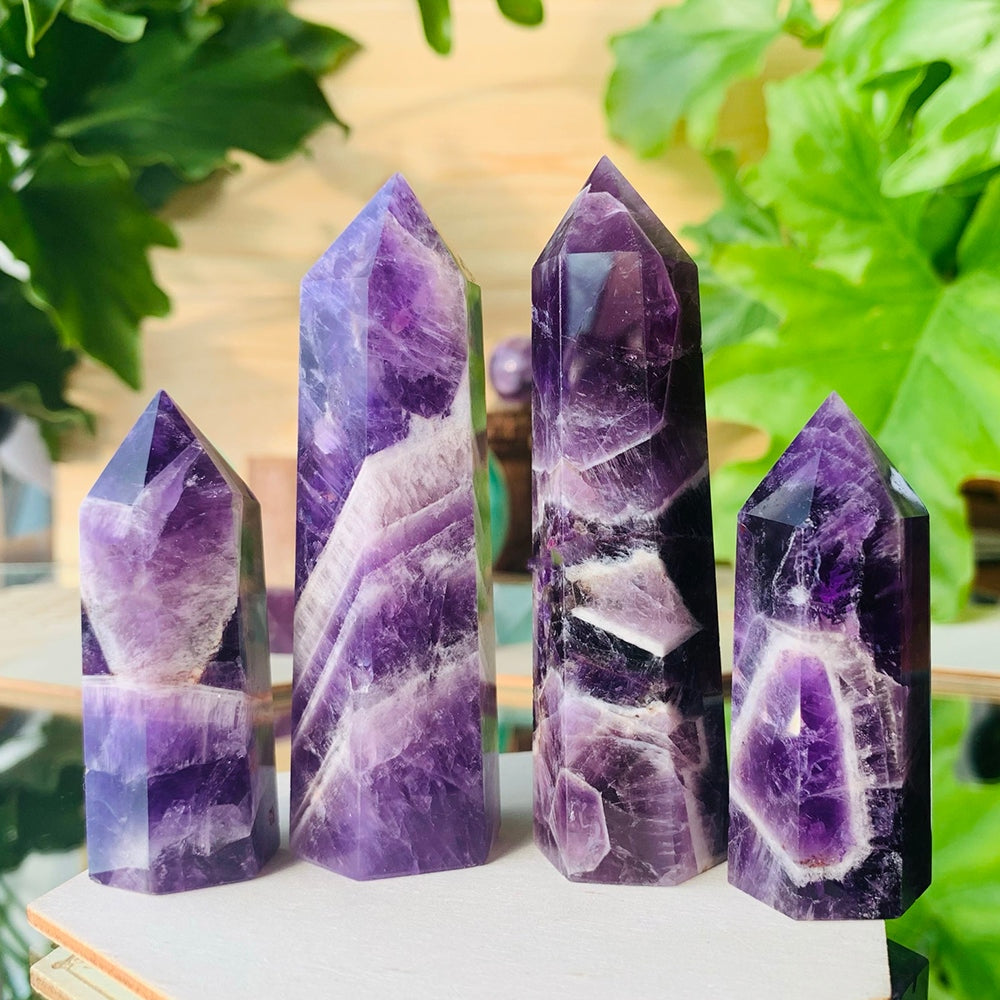Four polished dream amethyst points of different heights, each with its own purple and white banding