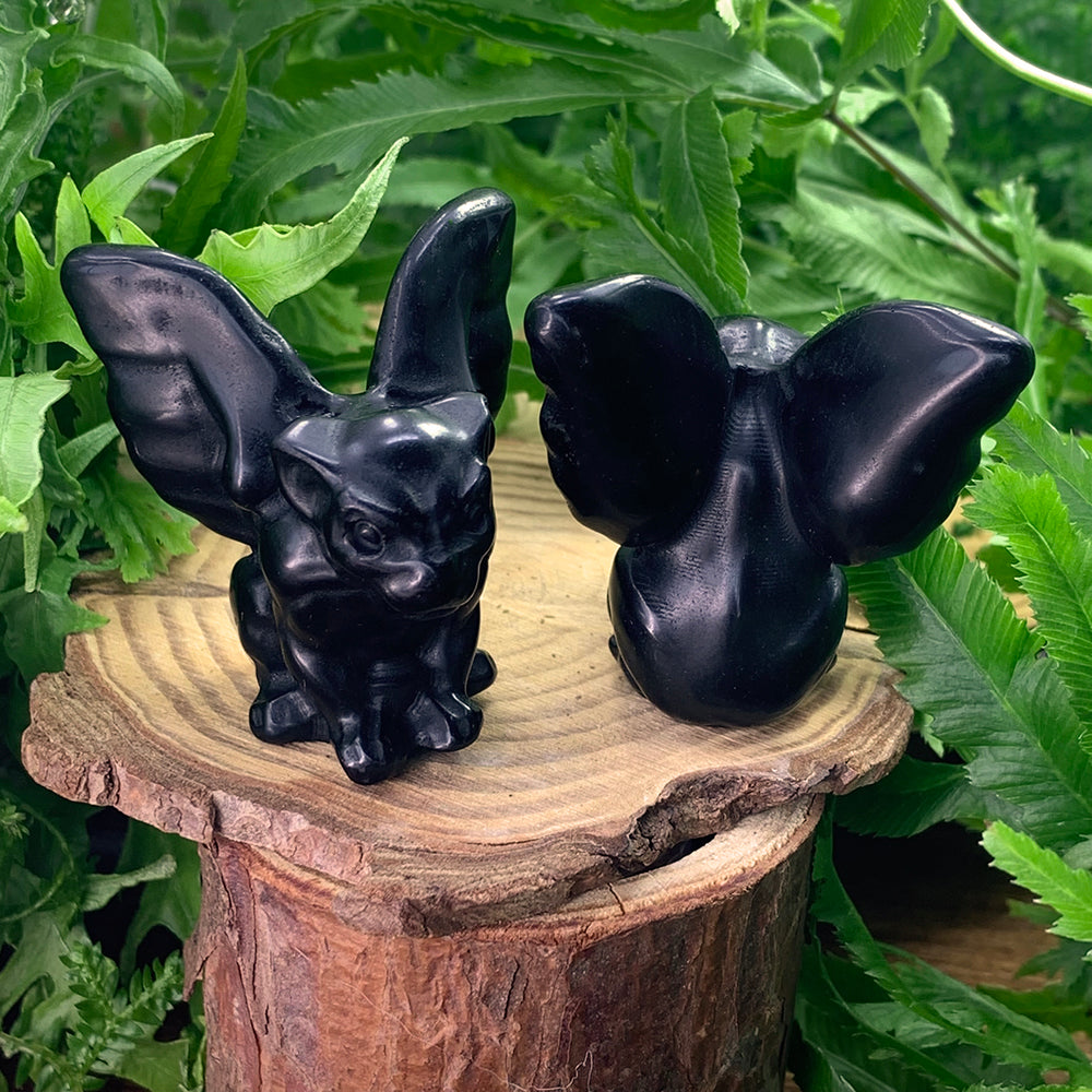 Two black agate gargoyles on a tree stump, one facing forward and one turned to show its carved back and wings