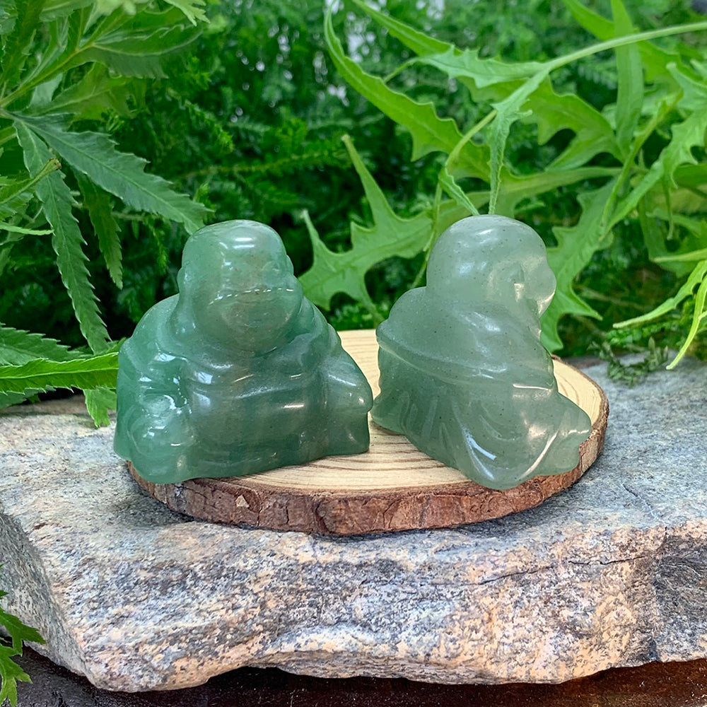 Two green quartz Buddhas on a wooden slice, one showing the carved front and one the carved robe at the back