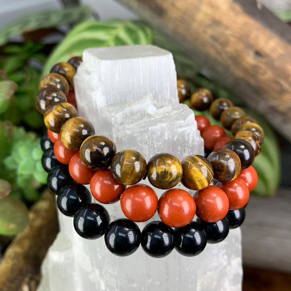 Tiger eye, red jasper and black obsidian bead bracelets stacked on a selenite tower