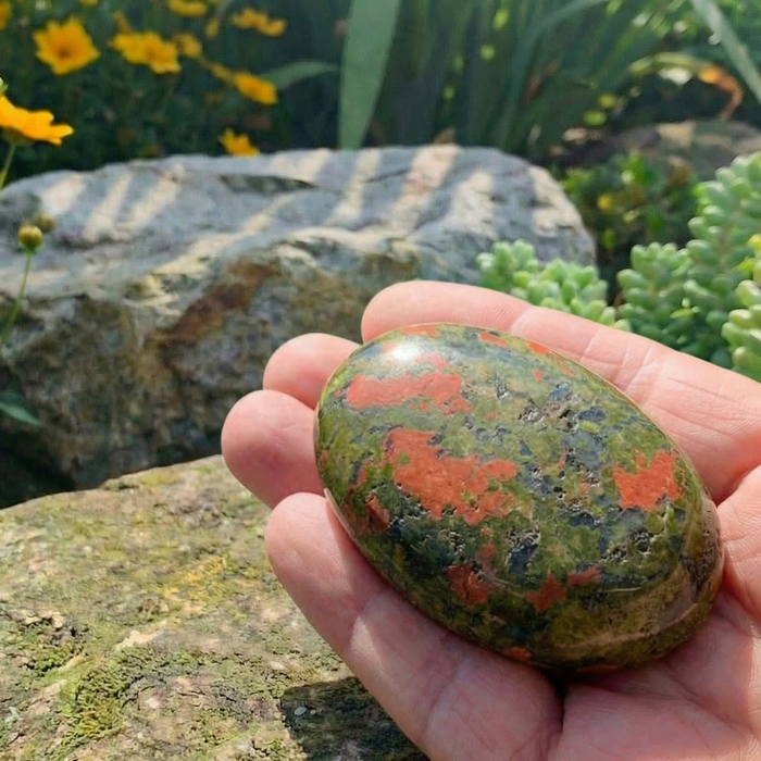 Green and pink unakite palmstone resting in an open hand