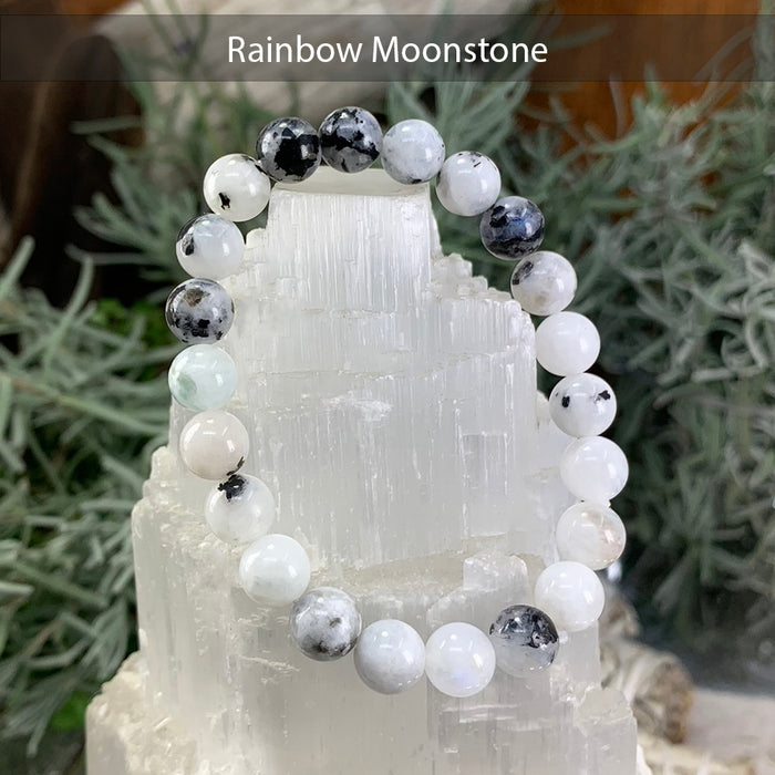 Rainbow moonstone bead bracelet in milky white with grey and black accents on a selenite tower