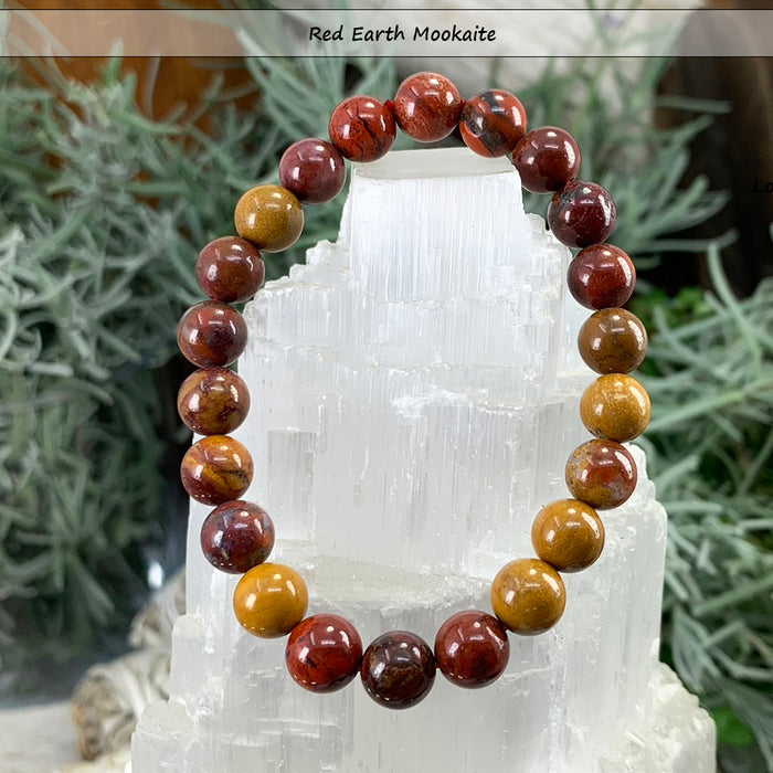 Red earth mookaite bead bracelet in brick red and gold on a selenite tower