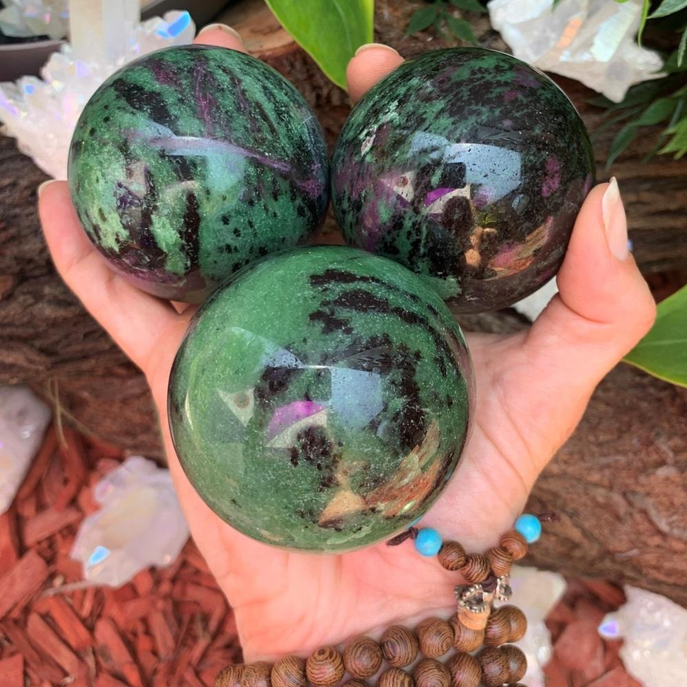 Three ruby in zoisite spheres held together, each with a different mix of green, black and magenta; one sphere is included