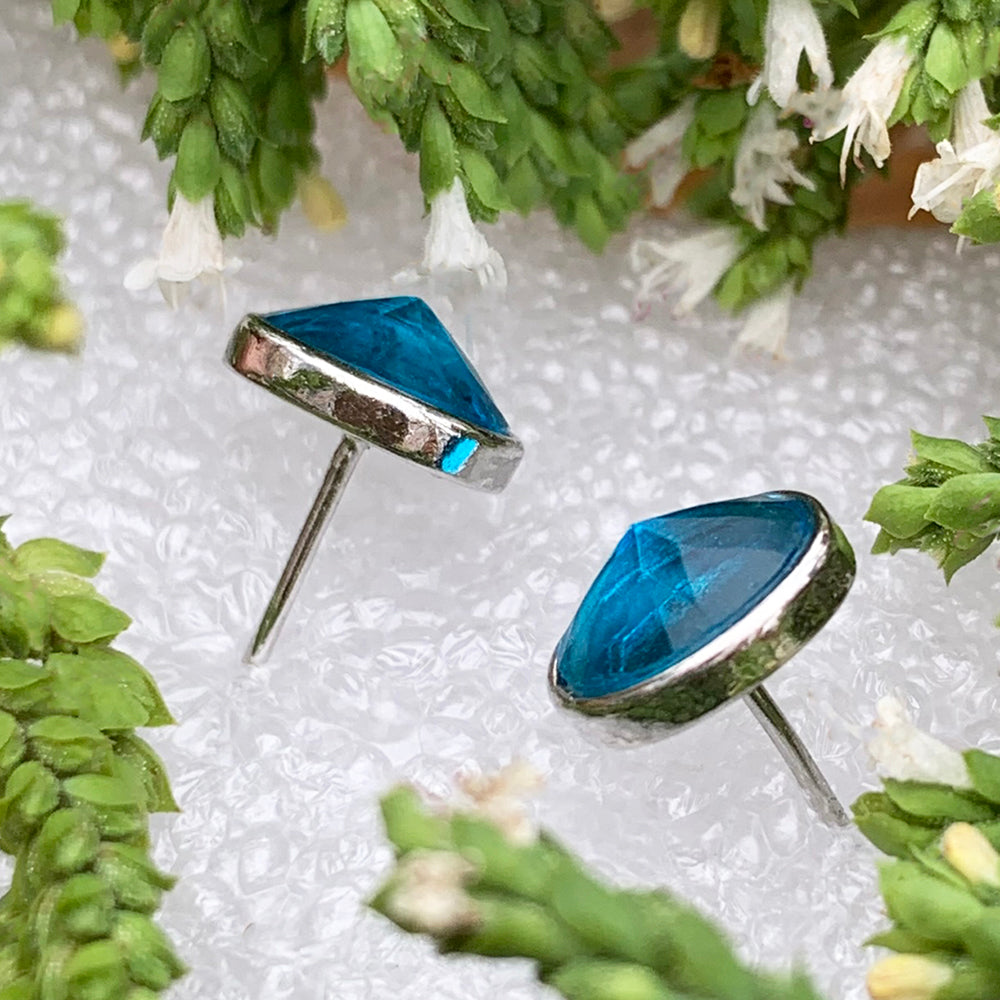 Side view of the two topaz studs showing their silver settings and posts